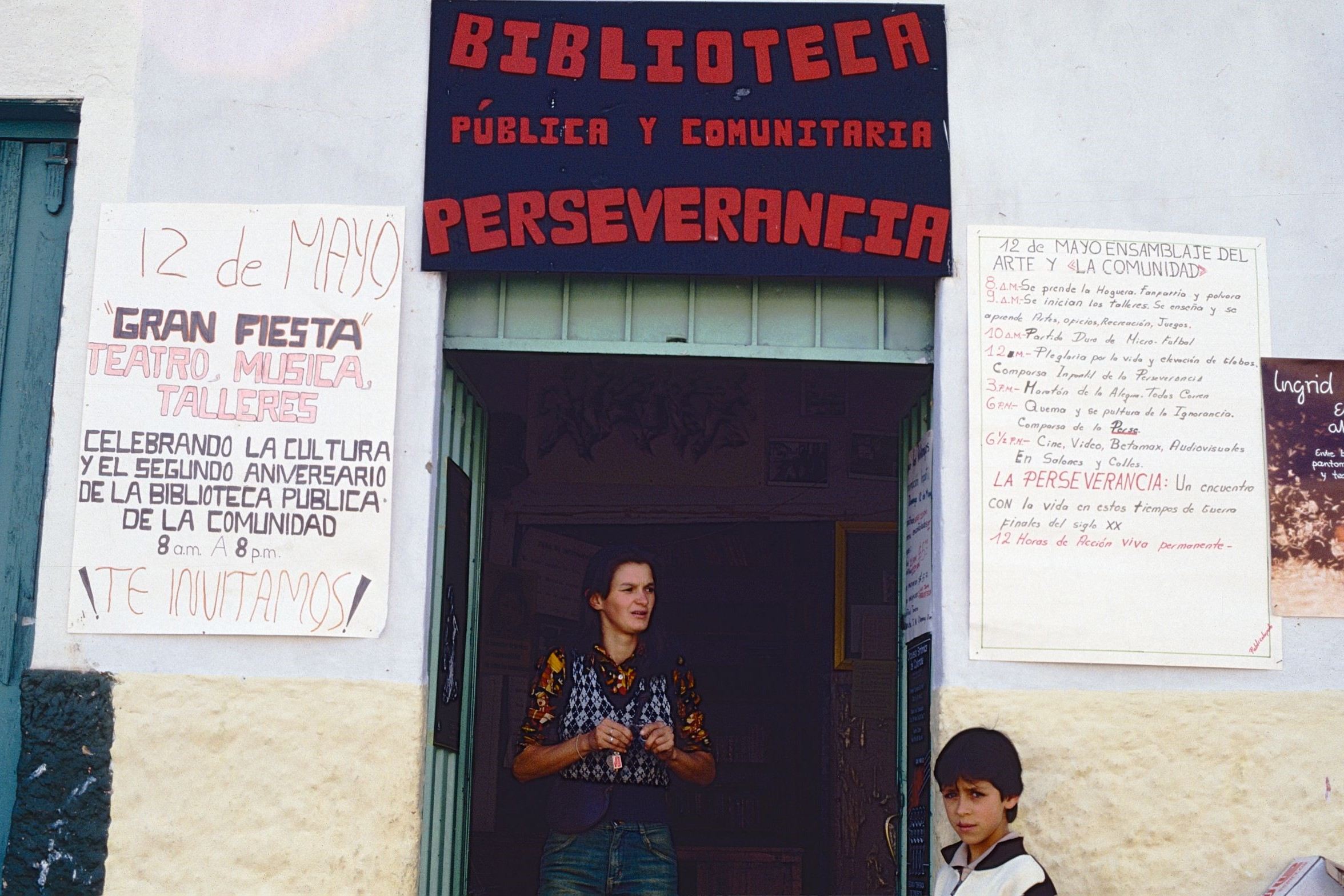 La Biblioteca con afiches La Bibliotecóloga del barrio en el portón de la biblioteca con afiches